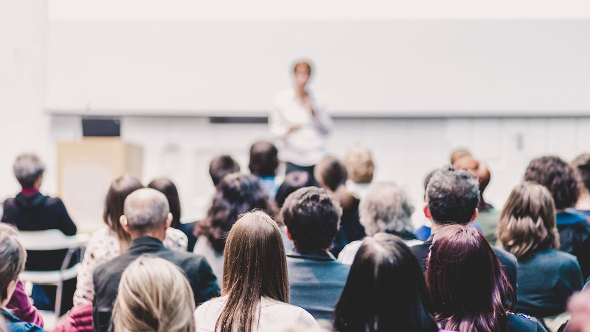 Ihmisiä istuu luentosalissa.