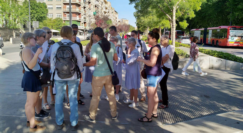 Ryhmä ihmisiä seisoo kesäkadulla Espanjassa.